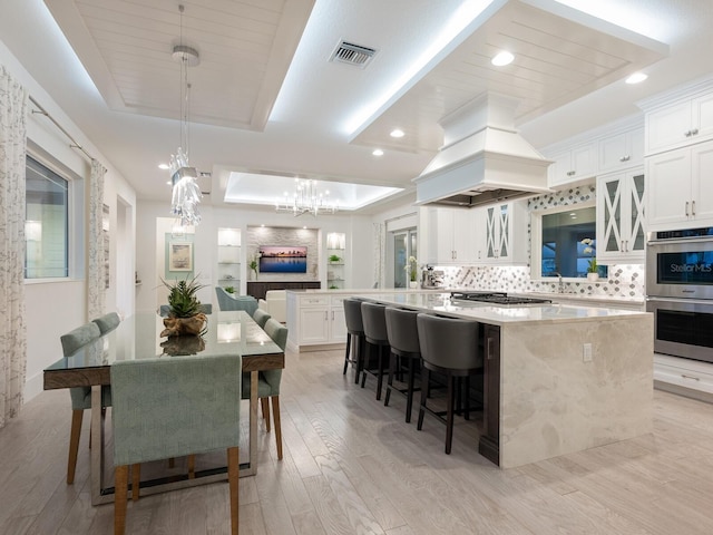 5630 Inspiration Ter, Bradenton, FL 34210 - kitchen with a raised ceiling, custom range hood, stainless steel appliances, a center island, and decorative backsplash