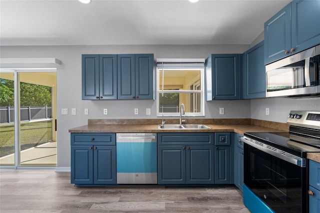 2405 Mistleto Ln, North Port, FL 34286 - kitchen with appliances with stainless steel finishes, blue cabinetry, and light wood finished floors