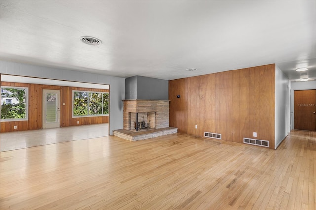 2850 Bon Air Ave, Sarasota, FL 34234 - unfurnished living room with light wood-style flooring, a fireplace, and wood walls