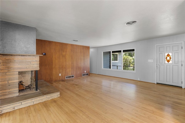 2850 Bon Air Ave, Sarasota, FL 34234 - unfurnished living room with light wood-type flooring, a stone fireplace, and wooden walls
