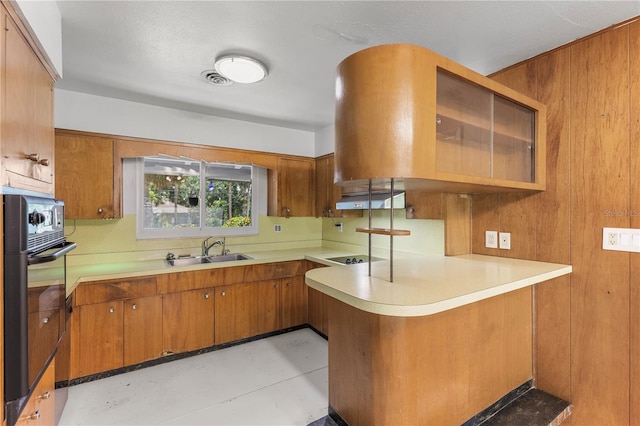 2850 Bon Air Ave, Sarasota, FL 34234 - kitchen featuring black oven, brown cabinetry, a peninsula, and light countertops