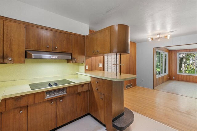 2850 Bon Air Ave, Sarasota, FL 34234 - kitchen featuring under cabinet range hood, brown cabinets, black electric stovetop, and light countertops