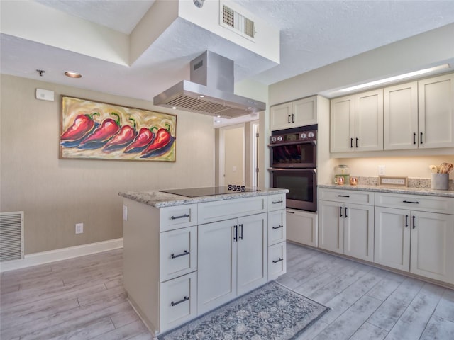 123 Tidy Island Blvd, Bradenton, FL 34210 - kitchen with wall chimney range hood, double oven, black electric stovetop, light wood-type flooring, and a kitchen island
