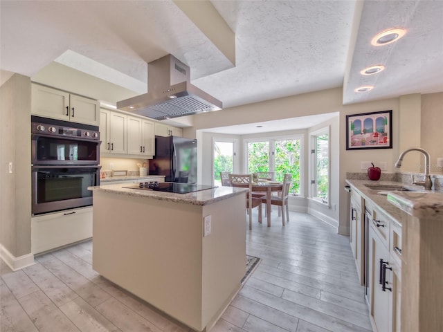 123 Tidy Island Blvd, Bradenton, FL 34210 - kitchen with black appliances, island range hood, light wood-type flooring, a kitchen island, and a textured ceiling