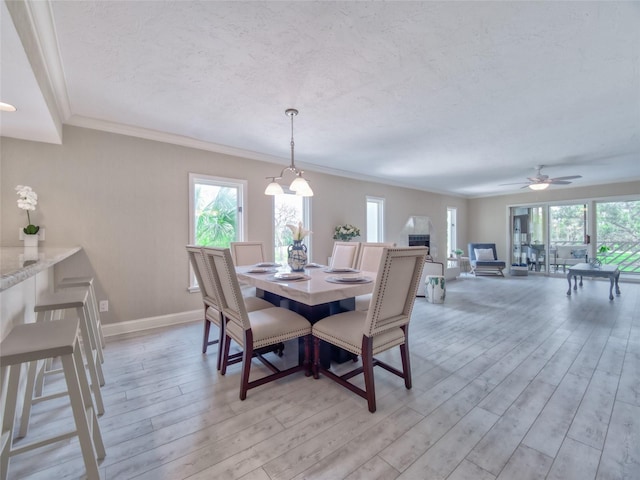123 Tidy Island Blvd, Bradenton, FL 34210 - dining room featuring light wood-style floors, a textured ceiling, ceiling fan, and crown molding