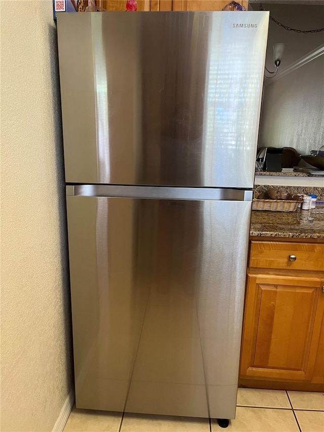 900 La Costa Cir Unit 4, Sarasota, FL 34237 - kitchen view of freestanding refrigerator, dark stone countertops, brown cabinets, and ornamental molding