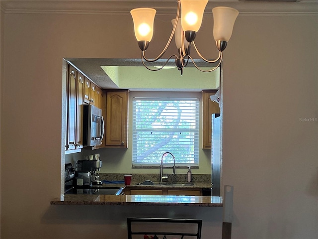 900 La Costa Cir Unit 4, Sarasota, FL 34237 - kitchen featuring stainless steel microwave, stove, crown molding, a chandelier, and brown cabinetry