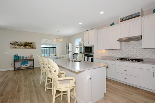16231 Tradewind Ter, Bradenton, FL 34211 - kitchen featuring under cabinet range hood, appliances with stainless steel finishes, light wood finished floors, white cabinets, and recessed lighting