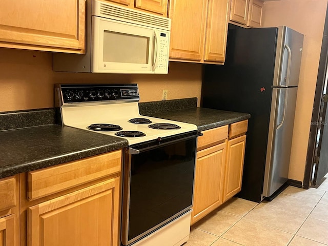 507 Cloudcroft Dr, Deltona, FL 32738 - kitchen with electric range, white microwave, freestanding refrigerator, light tile patterned floors, and dark countertops