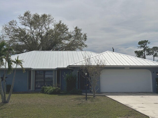 22321 Yonkers Ave, Port Charlotte, FL 33952 - view of front of home featuring a garage, a front lawn, driveway, stucco siding, and a metal roof