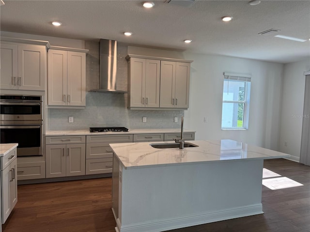 17134 Savory Mist Cir, Bradenton, FL 34211 - kitchen with wall chimney exhaust hood, appliances with stainless steel finishes, dark wood-type flooring, tasteful backsplash, and light stone counters