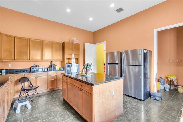 4105 37th St E, Bradenton, FL 34208 - kitchen with freestanding refrigerator, a center island, tile patterned floors, dark stone counters, and recessed lighting