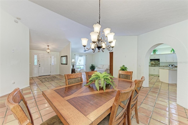 3217 Oak Grove Dr, Sarasota, FL 34243 - dining room with a chandelier, light tile patterned floors, and arched walkways