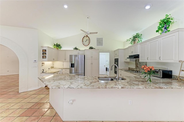 3217 Oak Grove Dr, Sarasota, FL 34243 - kitchen featuring stainless steel fridge with ice dispenser, under cabinet range hood, a peninsula, arched walkways, and light stone counters