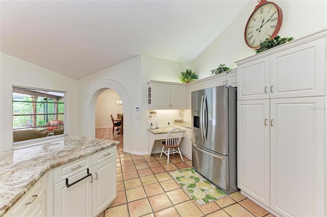 3217 Oak Grove Dr, Sarasota, FL 34243 - kitchen with stainless steel fridge with ice dispenser, vaulted ceiling, arched walkways, light tile patterned floors, and white cabinetry