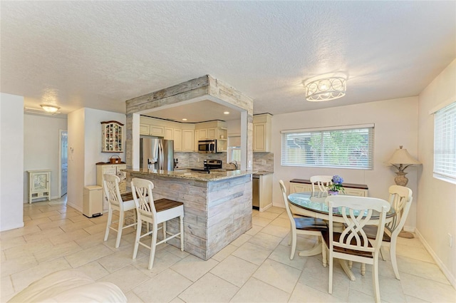 5415 13th Avenue Dr W, Bradenton, FL 34209 - kitchen featuring appliances with stainless steel finishes, tasteful backsplash, light stone counters, a breakfast bar, and a textured ceiling