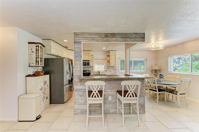 5415 13th Avenue Dr W, Bradenton, FL 34209 - kitchen featuring appliances with stainless steel finishes, a breakfast bar area, glass insert cabinets, light tile patterned floors, and a textured ceiling