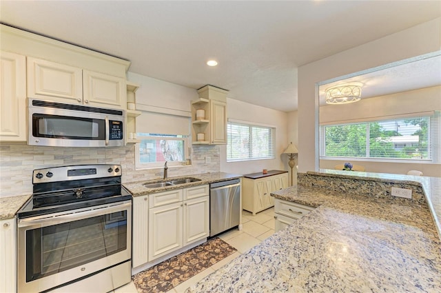 5415 13th Avenue Dr W, Bradenton, FL 34209 - kitchen featuring appliances with stainless steel finishes, open shelves, tasteful backsplash, light tile patterned floors, and light stone countertops