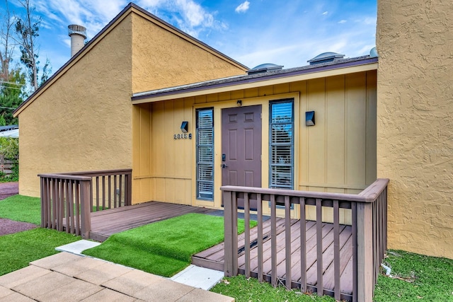 2315 Riverwood Pines Dr, Sarasota, FL 34231 - view of exterior entry with a lawn, stucco siding, and a deck