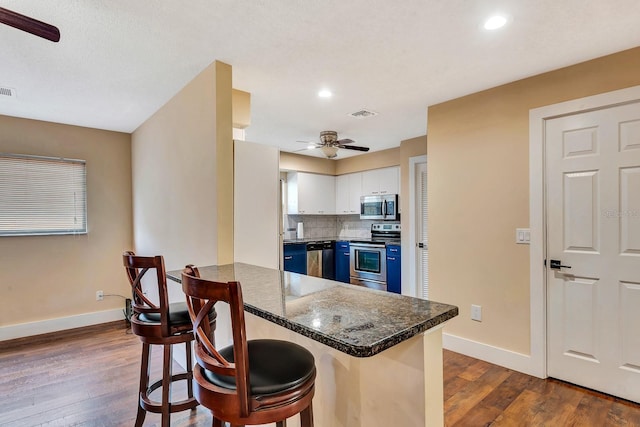 2315 Riverwood Pines Dr, Sarasota, FL 34231 - kitchen featuring stainless steel appliances, ceiling fan, blue cabinetry, a breakfast bar area, and dark wood-type flooring