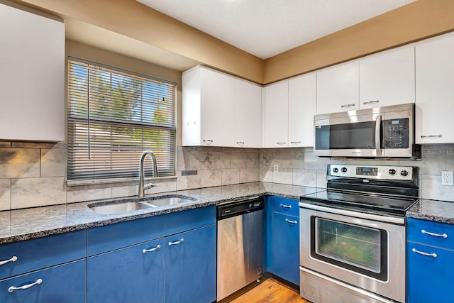 2315 Riverwood Pines Dr, Sarasota, FL 34231 - kitchen with stainless steel appliances, blue cabinetry, decorative backsplash, white cabinets, and dark stone counters