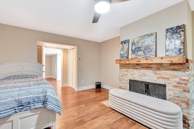 2315 Riverwood Pines Dr, Sarasota, FL 34231 - bedroom with light wood-style flooring, a stone fireplace, ceiling fan, and a closet