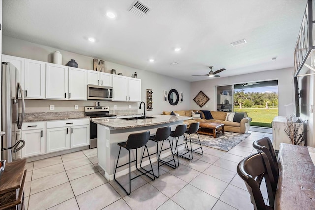 8979 Milestone Dr, Sarasota, FL 34238 - kitchen featuring appliances with stainless steel finishes, a breakfast bar, white cabinets, light stone countertops, and a ceiling fan