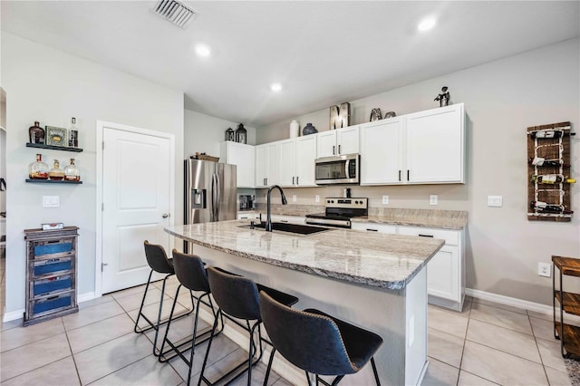8979 Milestone Dr, Sarasota, FL 34238 - kitchen featuring appliances with stainless steel finishes, a kitchen bar, light tile patterned floors, light stone countertops, and recessed lighting
