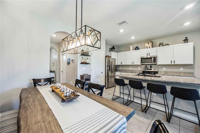 8979 Milestone Dr, Sarasota, FL 34238 - dining room with arched walkways, light tile patterned flooring, and recessed lighting
