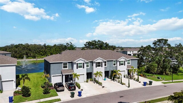 8979 Milestone Dr, Sarasota, FL 34238 - view of front of home featuring concrete driveway, an attached garage, a water view, stucco siding, and a front yard