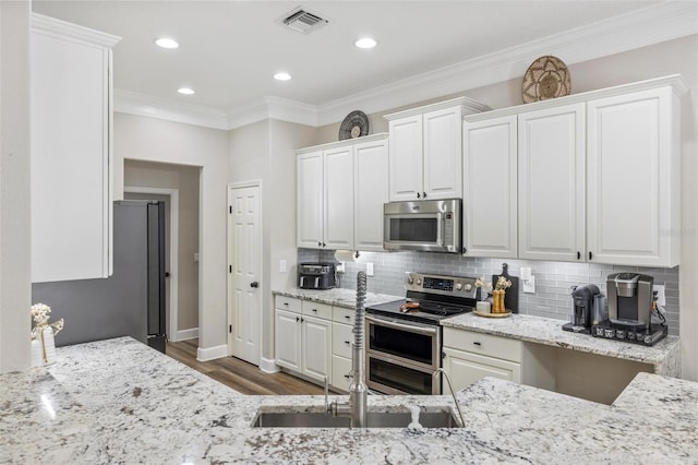 8840 Brookfield Ter, Bradenton, FL 34212 - kitchen featuring stainless steel appliances, white cabinets, decorative backsplash, crown molding, and recessed lighting