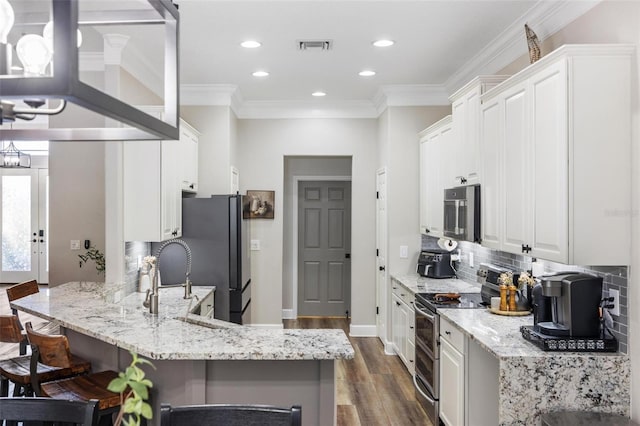 8840 Brookfield Ter, Bradenton, FL 34212 - kitchen with appliances with stainless steel finishes, a kitchen breakfast bar, a peninsula, tasteful backsplash, and dark wood-style flooring