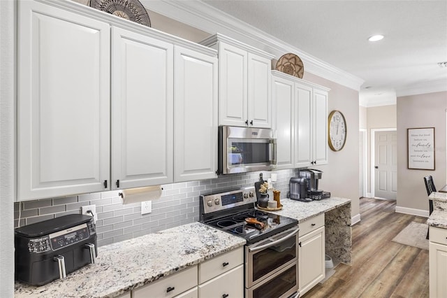 8840 Brookfield Ter, Bradenton, FL 34212 - kitchen featuring appliances with stainless steel finishes, crown molding, decorative backsplash, light wood-style flooring, and white cabinetry
