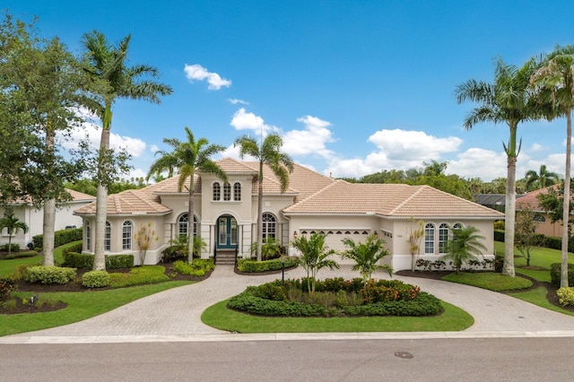 7144 Ashland Gln, Lakewood Ranch, FL 34202 - mediterranean / spanish house featuring curved driveway, an attached garage, stucco siding, and a tile roof