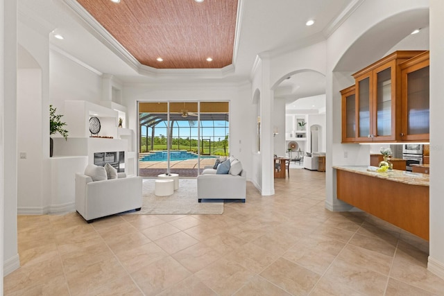 7144 Ashland Gln, Lakewood Ranch, FL 34202 - living area featuring a tray ceiling, ornamental molding, recessed lighting, arched walkways, and light tile patterned floors