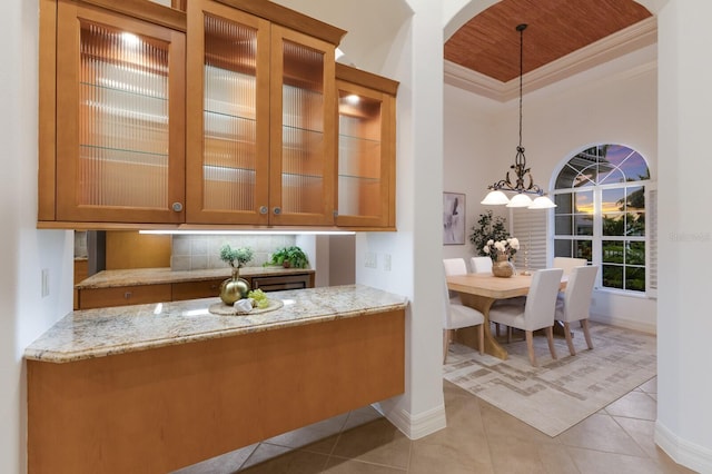 7144 Ashland Gln, Lakewood Ranch, FL 34202 - kitchen featuring backsplash, light stone countertops, glass insert cabinets, arched walkways, and ornamental molding