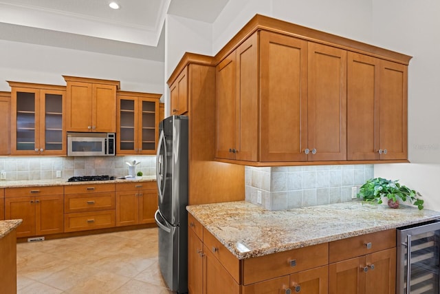 7144 Ashland Gln, Lakewood Ranch, FL 34202 - kitchen featuring appliances with stainless steel finishes, wine cooler, brown cabinets, decorative backsplash, and light stone countertops