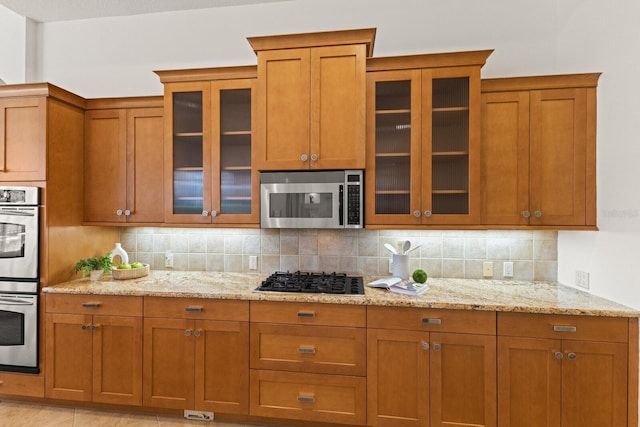 7144 Ashland Gln, Lakewood Ranch, FL 34202 - kitchen with stainless steel appliances, brown cabinetry, and backsplash
