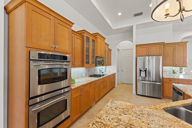 7144 Ashland Gln, Lakewood Ranch, FL 34202 - kitchen featuring stainless steel appliances, tasteful backsplash, light stone counters, brown cabinets, and recessed lighting
