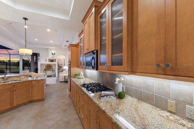 7144 Ashland Gln, Lakewood Ranch, FL 34202 - kitchen featuring a raised ceiling, gas cooktop, tasteful backsplash, light stone counters, and recessed lighting
