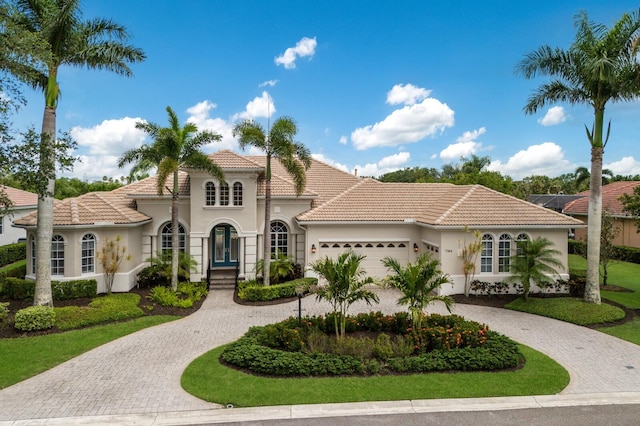 7144 Ashland Gln, Lakewood Ranch, FL 34202 - mediterranean / spanish home with curved driveway, a tiled roof, a garage, stucco siding, and french doors