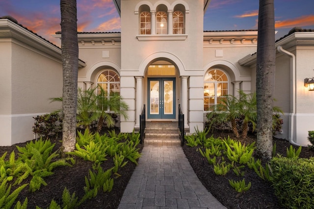 7144 Ashland Gln, Lakewood Ranch, FL 34202 - exterior entry at dusk featuring french doors and stucco siding