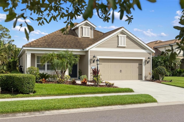12261 Stuart Dr, Venice, FL 34293 - view of front of house featuring a garage, driveway, a front lawn, covered porch, and a tile roof