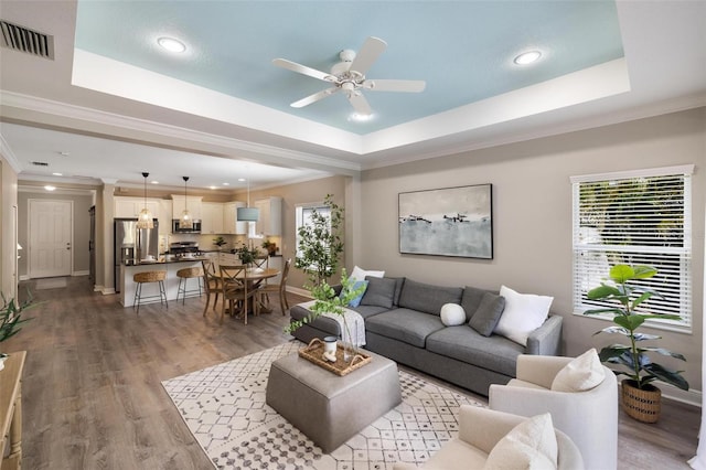 12261 Stuart Dr, Venice, FL 34293 - living room featuring a raised ceiling, ornamental molding, ceiling fan, light wood finished floors, and recessed lighting