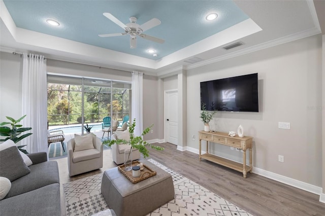 12261 Stuart Dr, Venice, FL 34293 - living area with a raised ceiling, ceiling fan, wood finished floors, recessed lighting, and crown molding