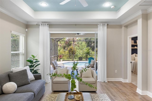 12261 Stuart Dr, Venice, FL 34293 - living room featuring ceiling fan, a tray ceiling, wood finished floors, a sunroom, and ornamental molding