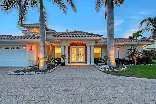 571 Birdie Ln, Longboat Key, FL 34228 - mediterranean / spanish-style house featuring an attached garage, french doors, a tile roof, and decorative driveway