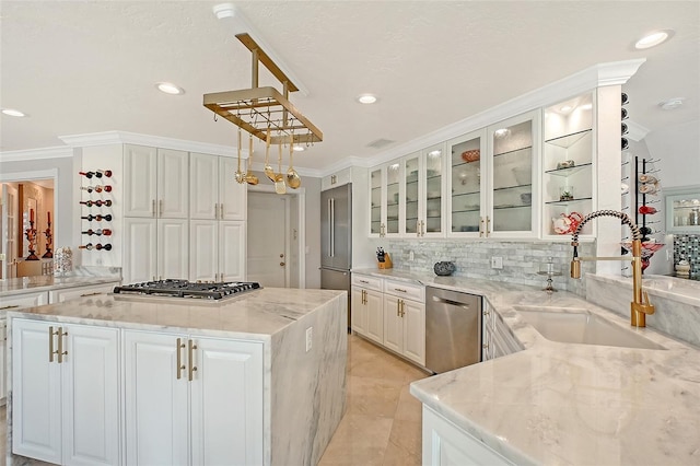 571 Birdie Ln, Longboat Key, FL 34228 - kitchen featuring stainless steel appliances, ornamental molding, white cabinetry, light stone countertops, and a center island