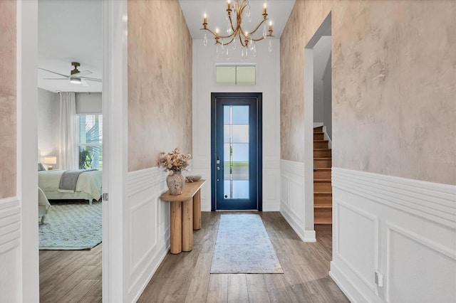 8209 Redonda Loop, Lakewood Ranch, FL 34202 - entryway with wainscoting, a chandelier, wood finished floors, a decorative wall, and stairway