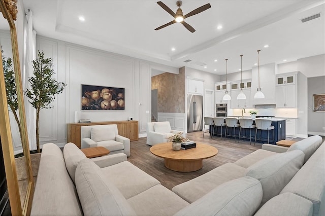 8209 Redonda Loop, Lakewood Ranch, FL 34202 - living room with a decorative wall, a ceiling fan, recessed lighting, light wood finished floors, and wainscoting
